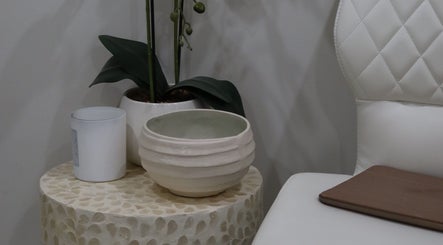 Elegant waiting area at Aesthetics By Kristen, Wollongong, with a white chair and decorative vase.