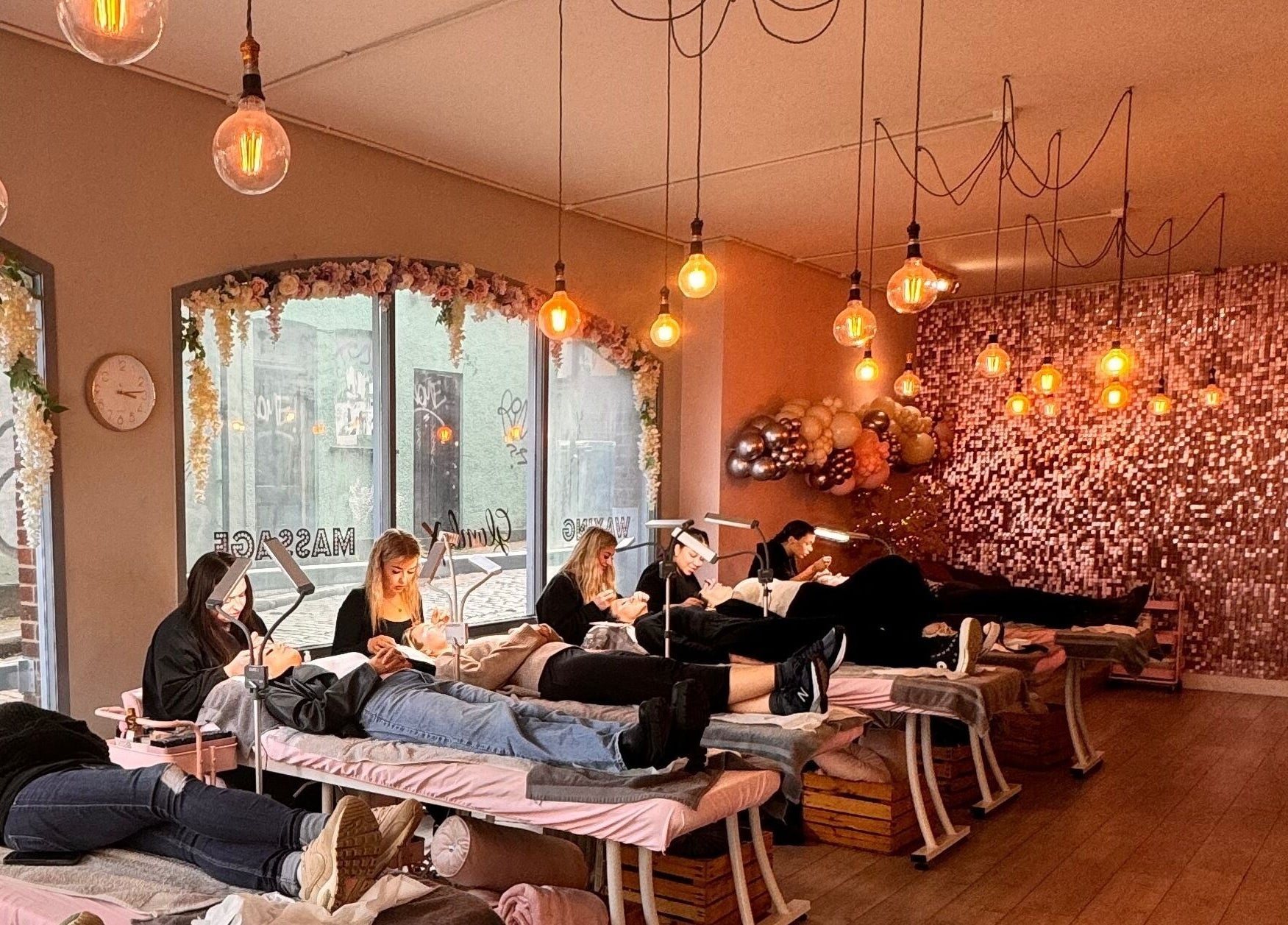 Chic beauty lounge at Glambox, Norwich, England, GB with clients receiving treatments under warm lighting.