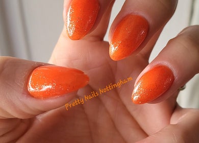 Sparkling orange nails at Pretty Nails Nottingham, Arnold, England, GB. Perfect for vibrant style enthusiasts.