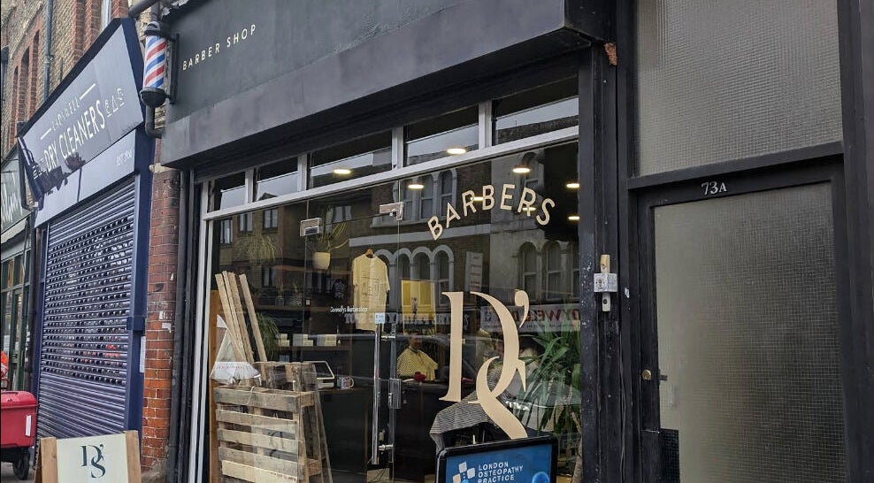 Street view of a stylish barbershop near Reviving Harmony, London, England, GB.