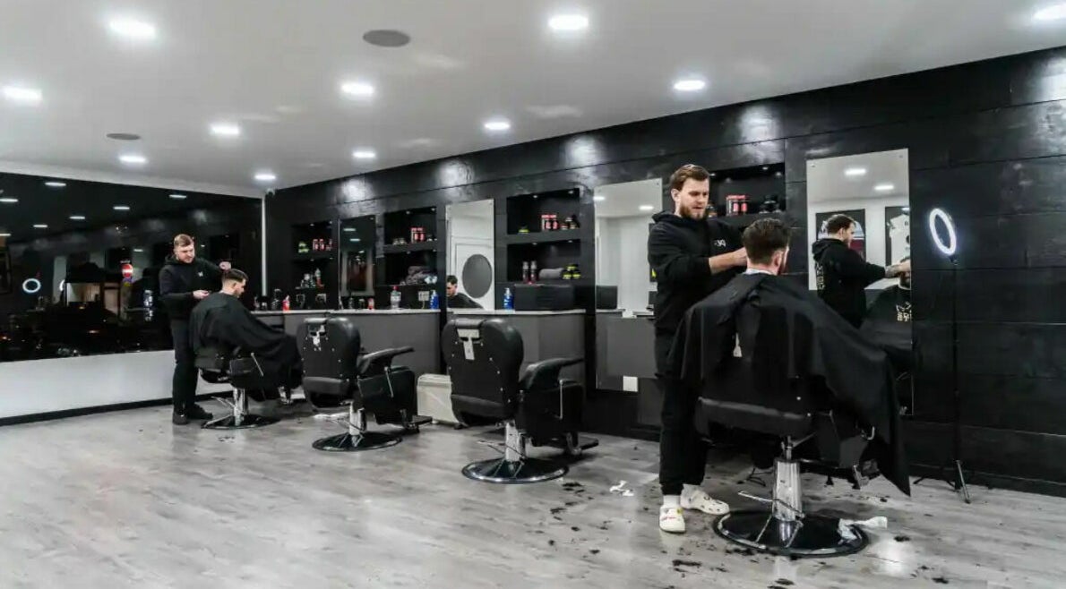 Modern interior of Kings Cuts barbershop in Epsom, England, GB, showcasing skilled barbers at work.