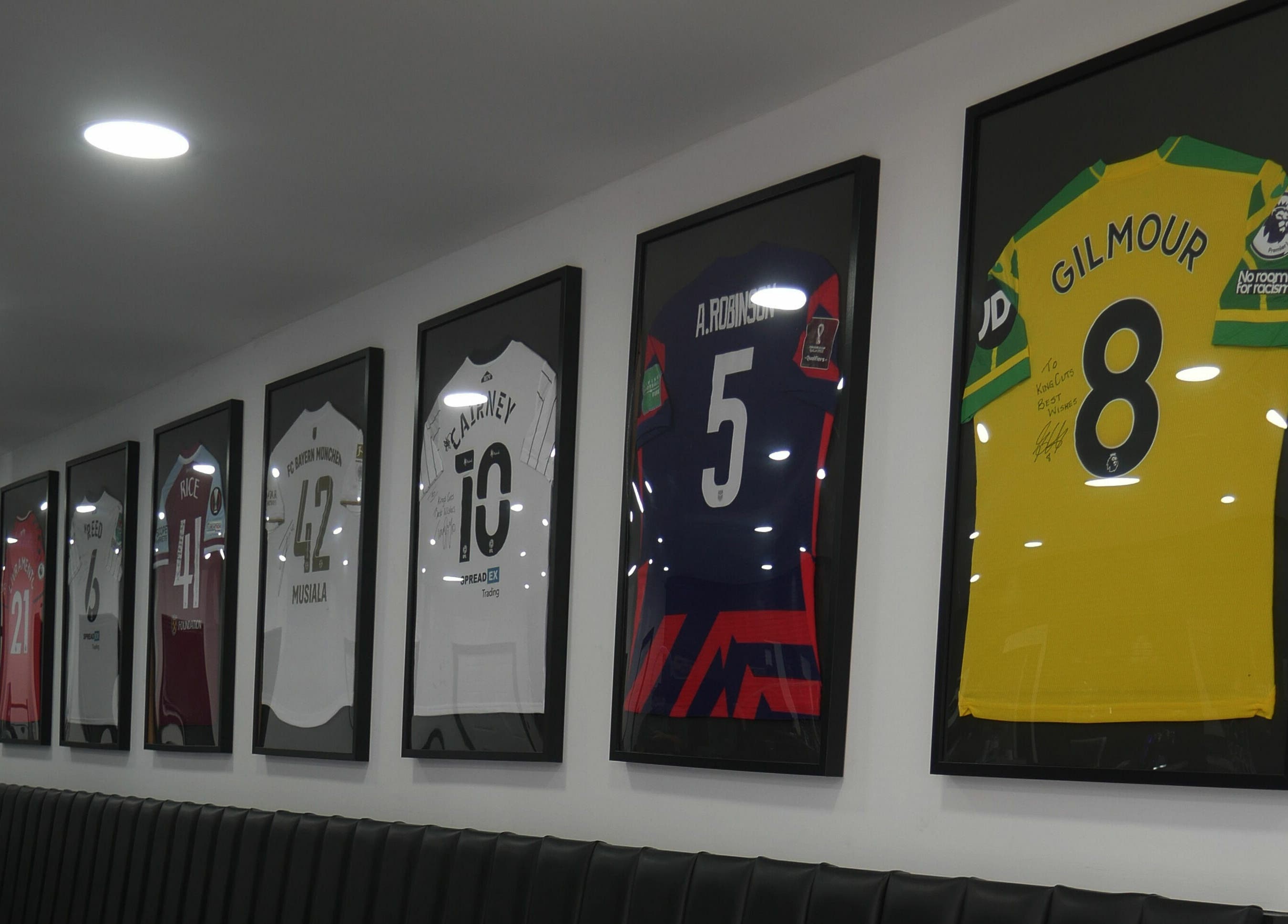 Framed jerseys decorate the wall at Kings Cuts, Epsom, England, GB offering a sporty vibe.