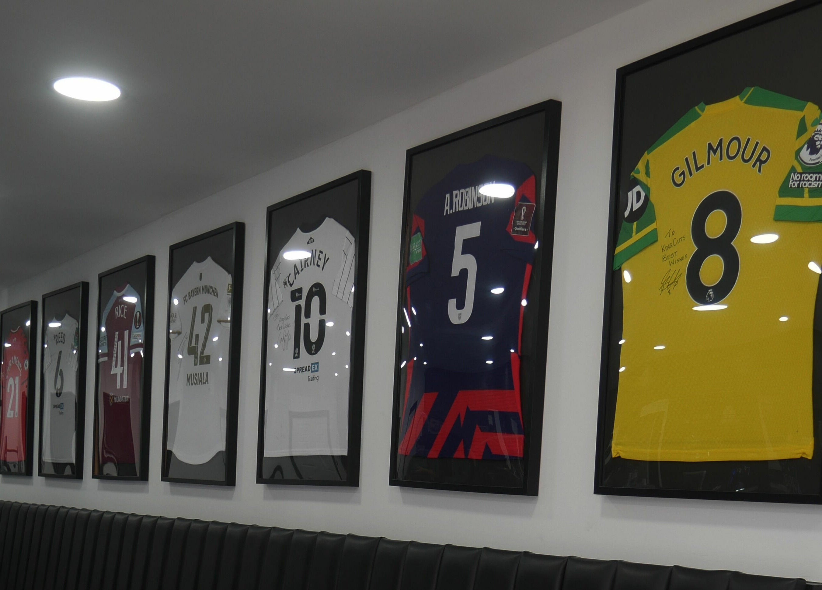 Framed jerseys decorate the wall at Kings Cuts, Epsom, England, GB offering a sporty vibe.
