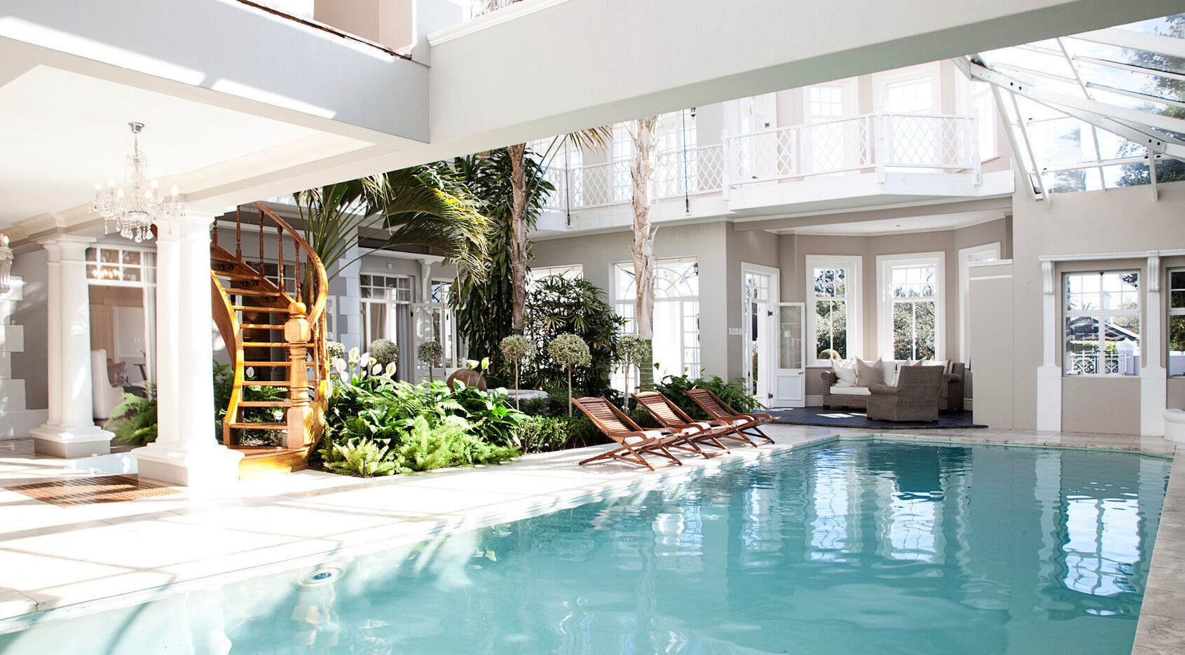 Luxurious indoor pool at Spa at Banksia, Cape Town, Western Cape, ZA with wooden loungers and lush greenery.
