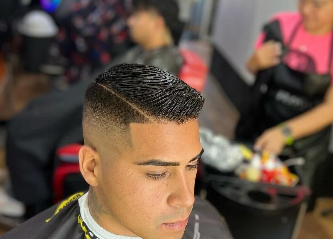 Cliente con corte moderno en Leo Barbershop, Talca, Maule, CL. Estilista trabajando al fondo.