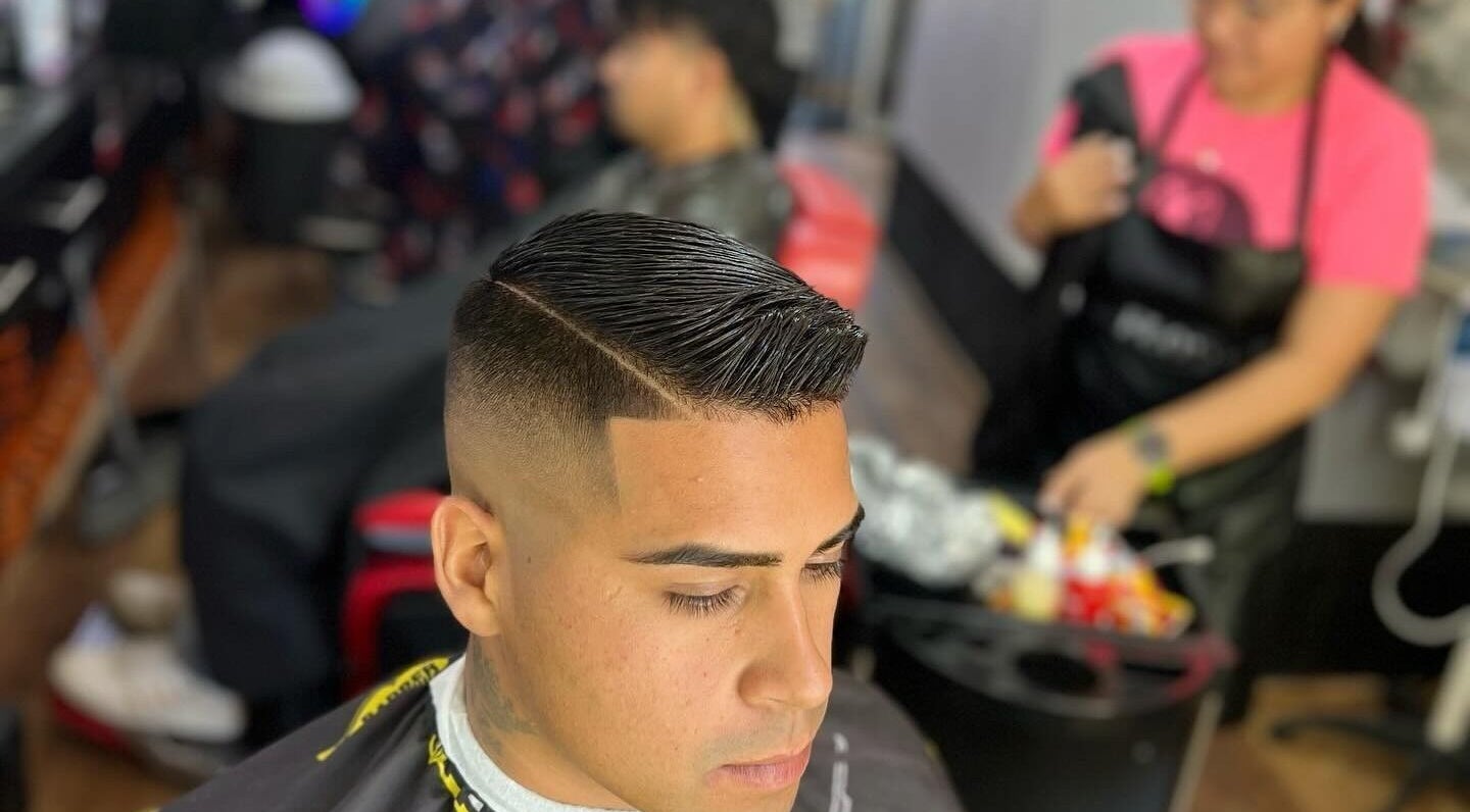 Cliente con corte moderno en Leo Barbershop, Talca, Maule, CL. Estilista trabajando al fondo.
