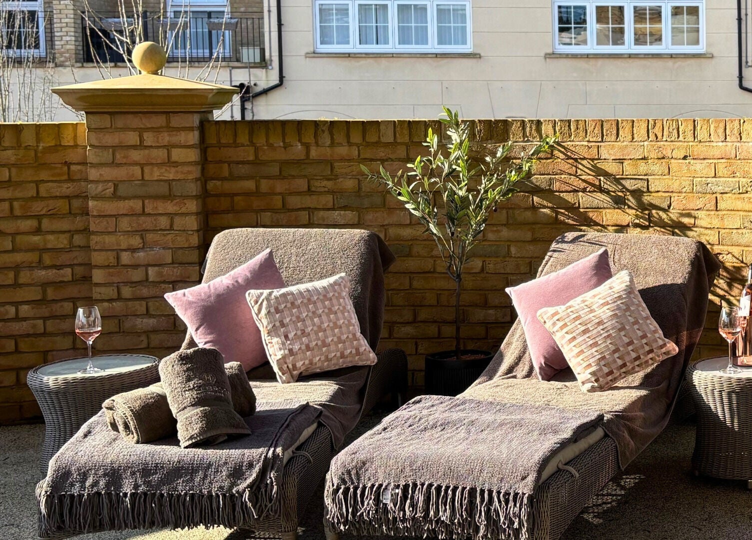 Relaxing patio setup at The Hillbrook, Sherborne, England with lounge chairs and wine under sunny skies.