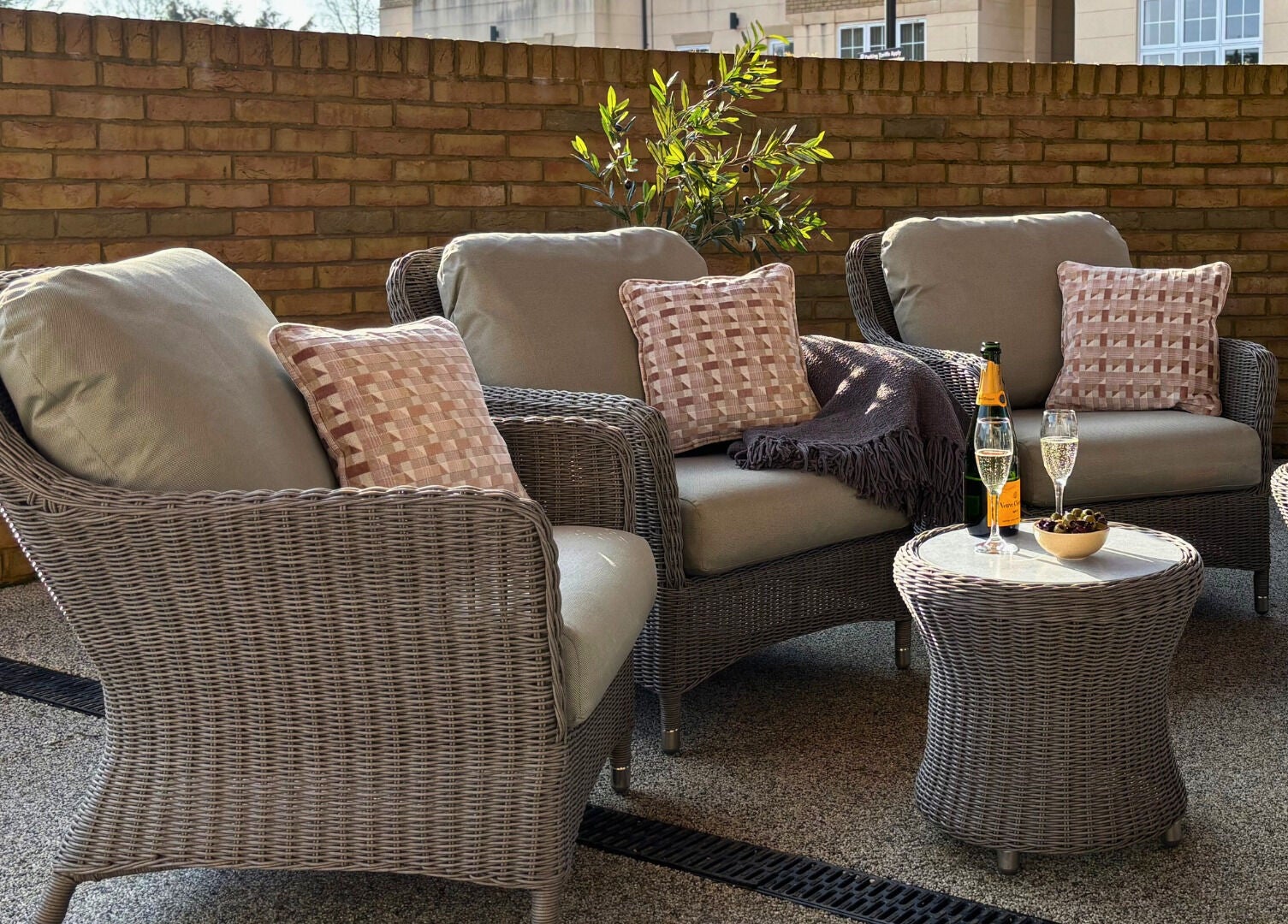 Cozy outdoor seating at The Hillbrook, Sherborne, England, GB set against a brick wall with refreshments.