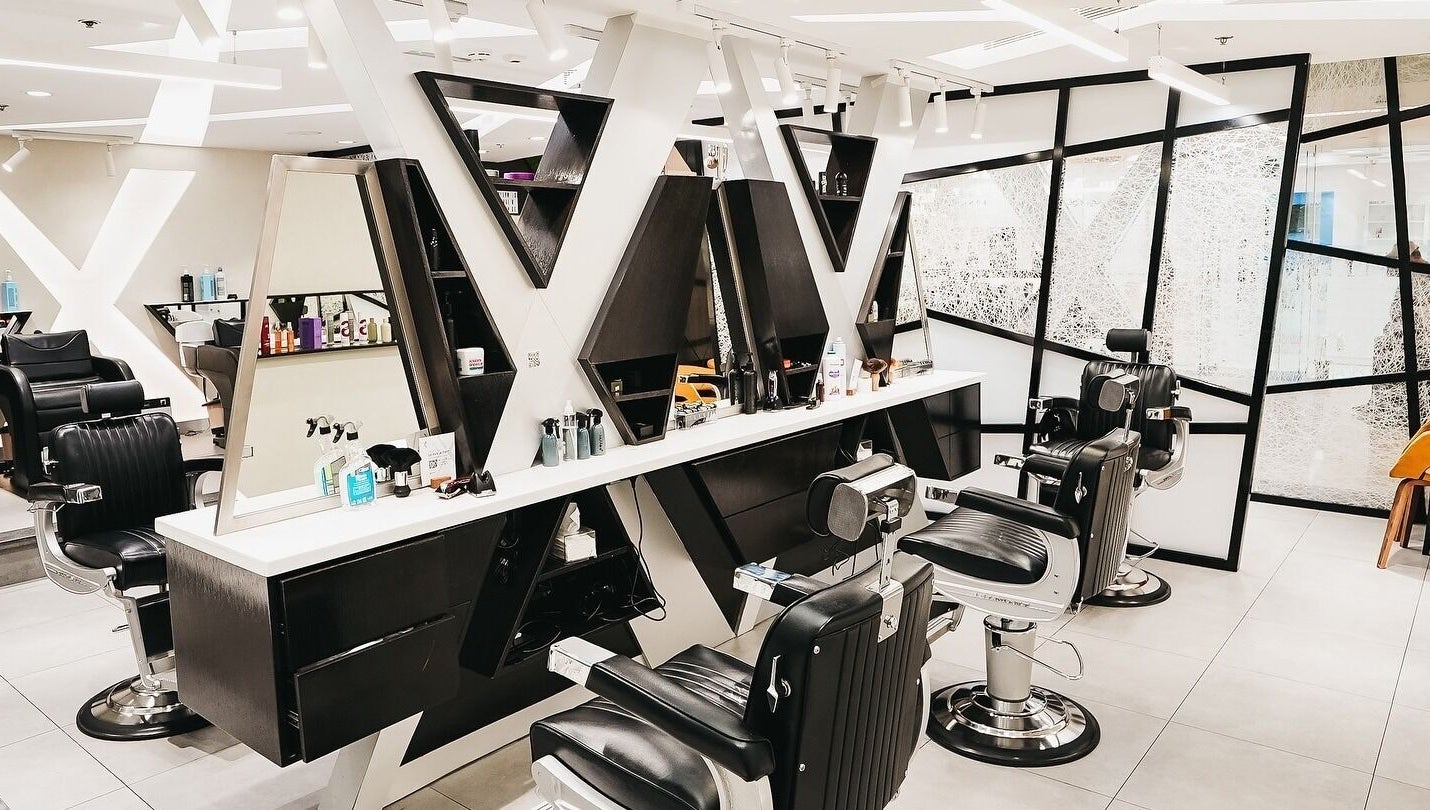 Modern salon interior at X Hair Lounge - City Center Mirdif, Dubai, AE with sleek black chairs and mirrors.