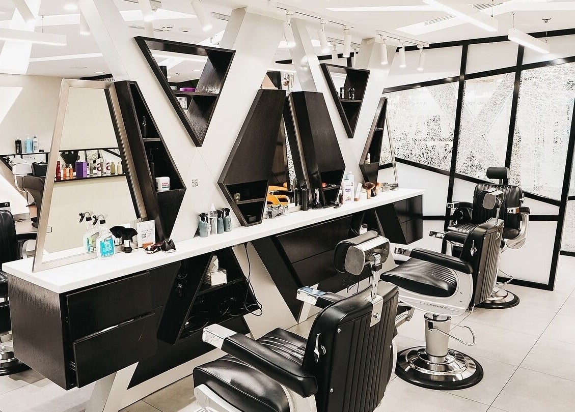 Modern salon interior at X Hair Lounge - City Center Mirdif, Dubai, AE with sleek black chairs and mirrors.