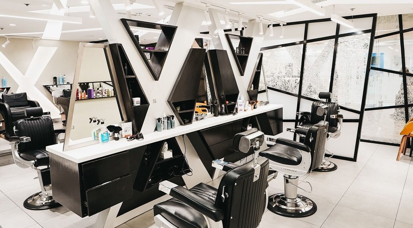 Modern salon interior at X Hair Lounge - City Center Mirdif, Dubai, AE with sleek black chairs and mirrors.