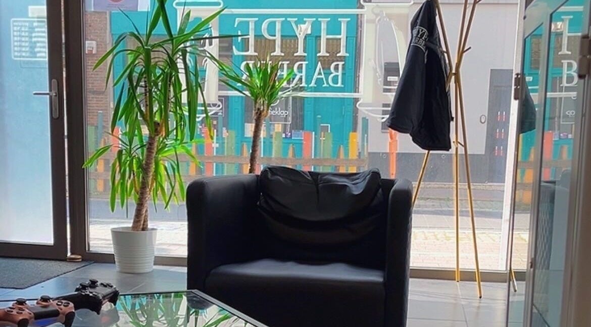 Stijlvolle zithoek bij HYPE BARBERSHOP in Antwerpen, Vlaams Gewest, BE met een moderne fauteuil en planten.