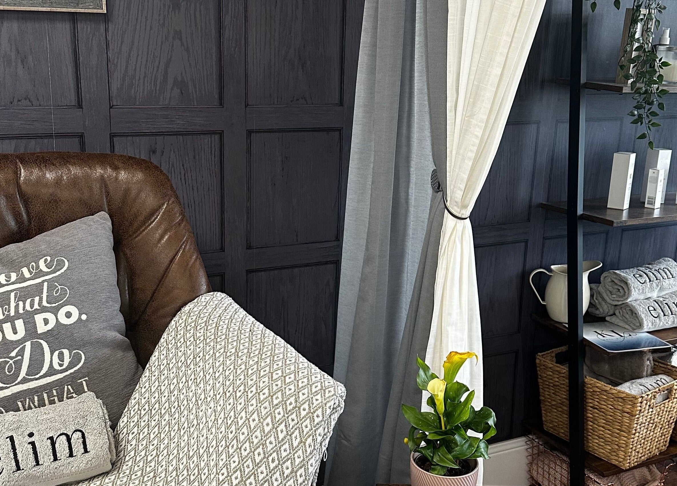 Cozy interior of KL Nail Studio, Newtown, Wales, GB, featuring a leather chair and wooden shelves with beauty products.