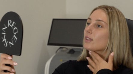 Woman admiring skin in Regen Skin mirror, Melbourne, Victoria, AU, highlighting beauty services.