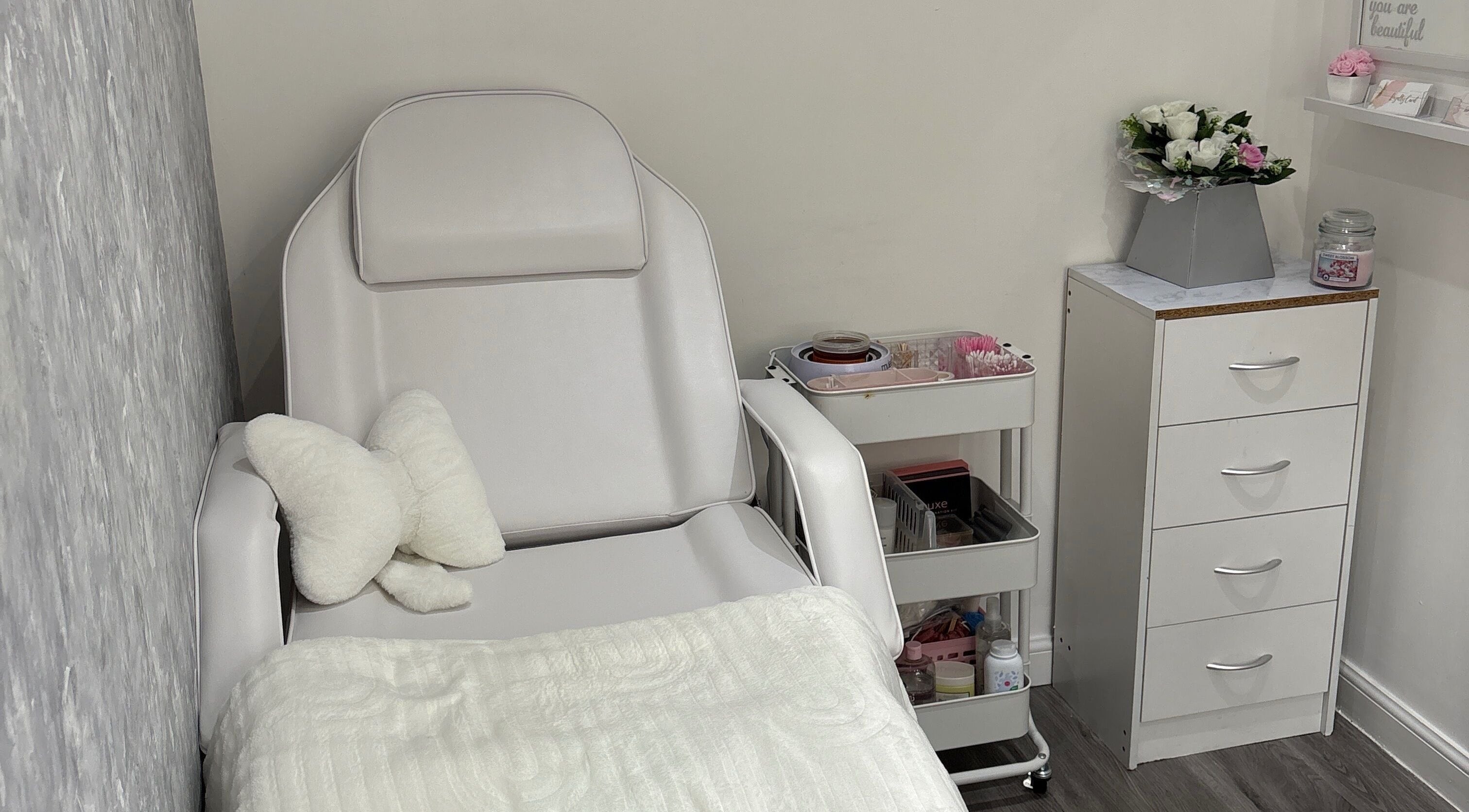 Cozy beauty treatment room at Ella Louise Beautyy, Rochdale, England, GB with plush chair and floral decor.