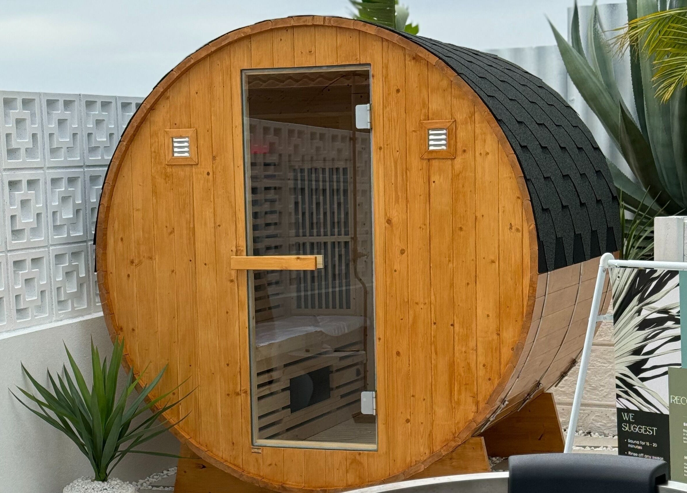 Wooden barrel sauna at Zen Zone Perth, Beldon, Western Australia, AU, surrounded by lush plants.