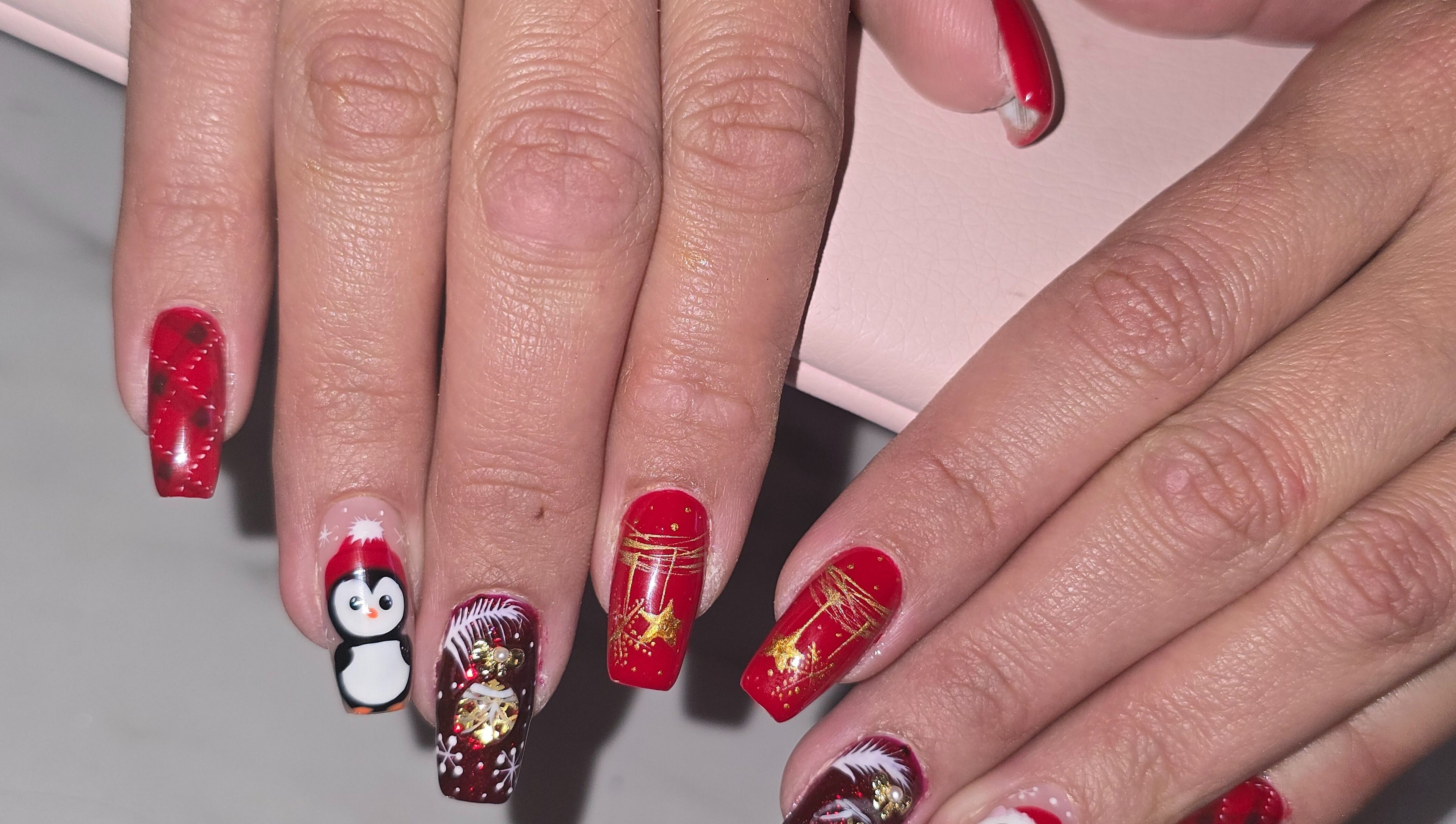 Art des ongles festif chez Lala Bellezza, Corte, Corse, FR, avec des motifs rouges et un pingouin.