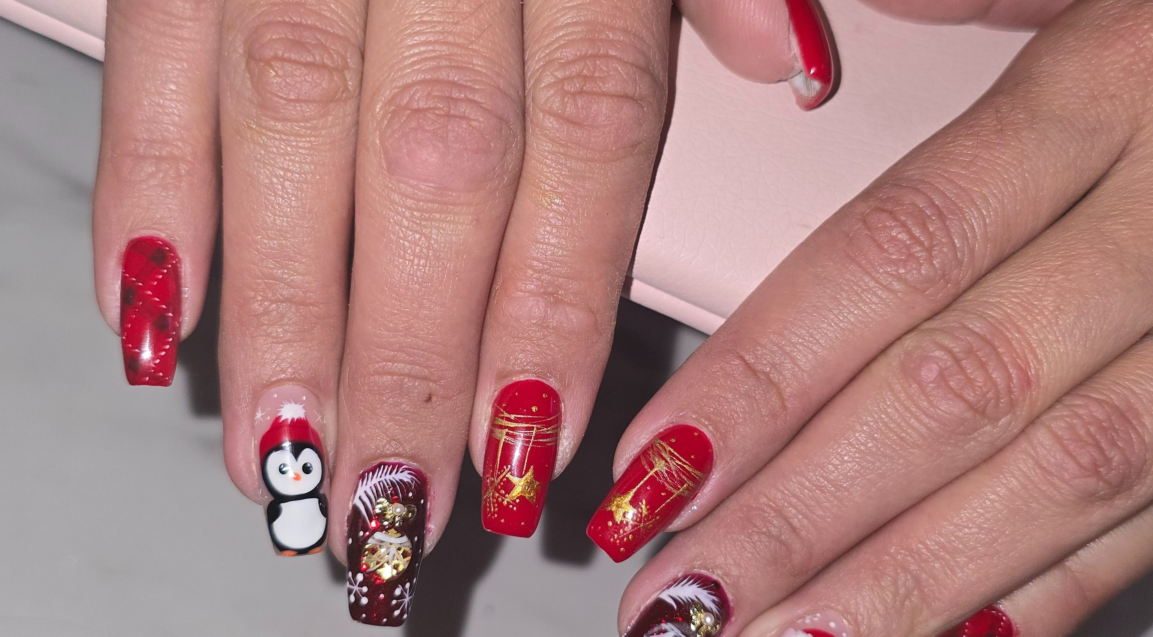 Art des ongles festif chez Lala Bellezza, Corte, Corse, FR, avec des motifs rouges et un pingouin.