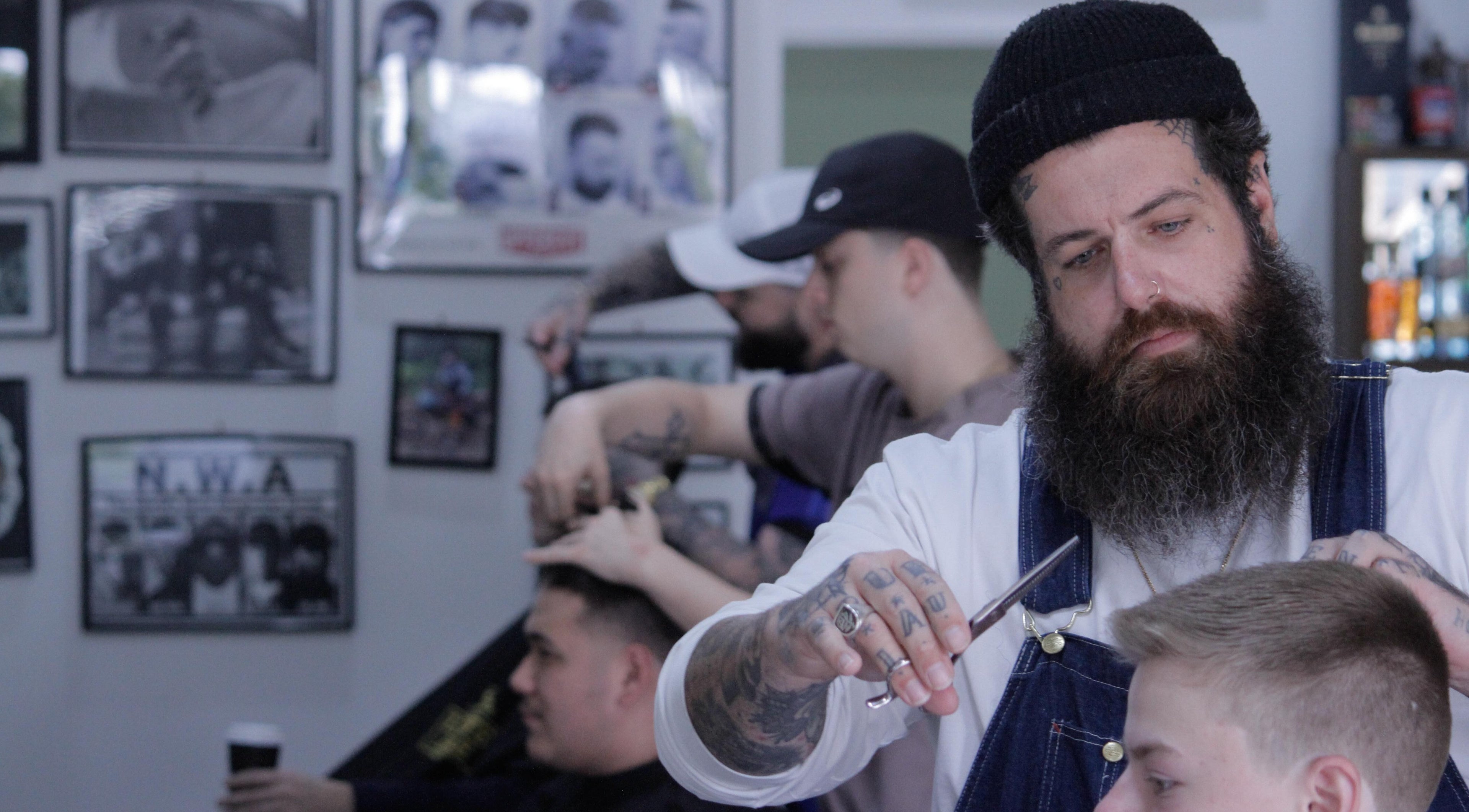 Skilled barber styling hair at Nine Lives Barbershop in Paradise Point, Queensland, AU.