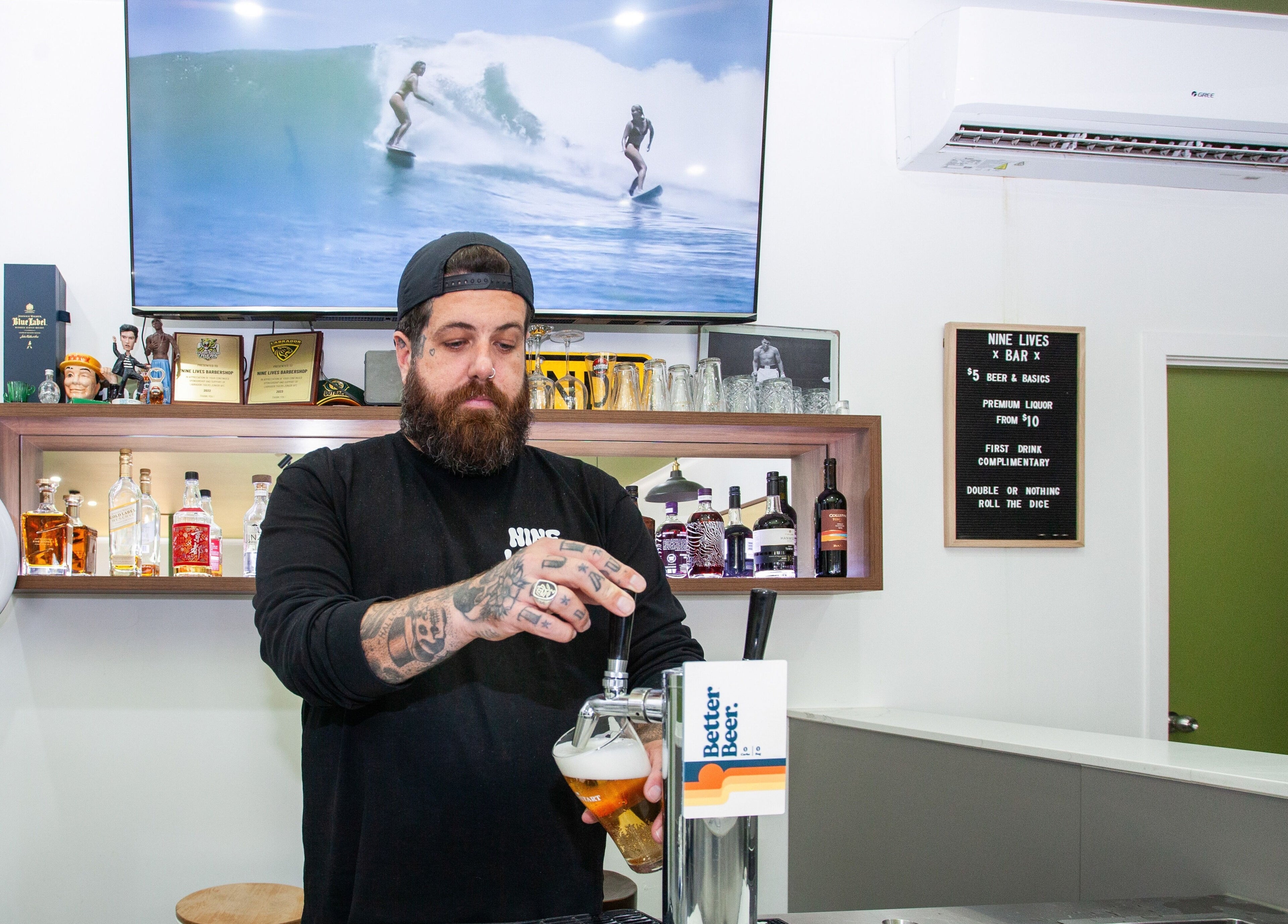 Bartender pouring beer at Nine Lives Barbershop, Paradise Point, Queensland, AU.
