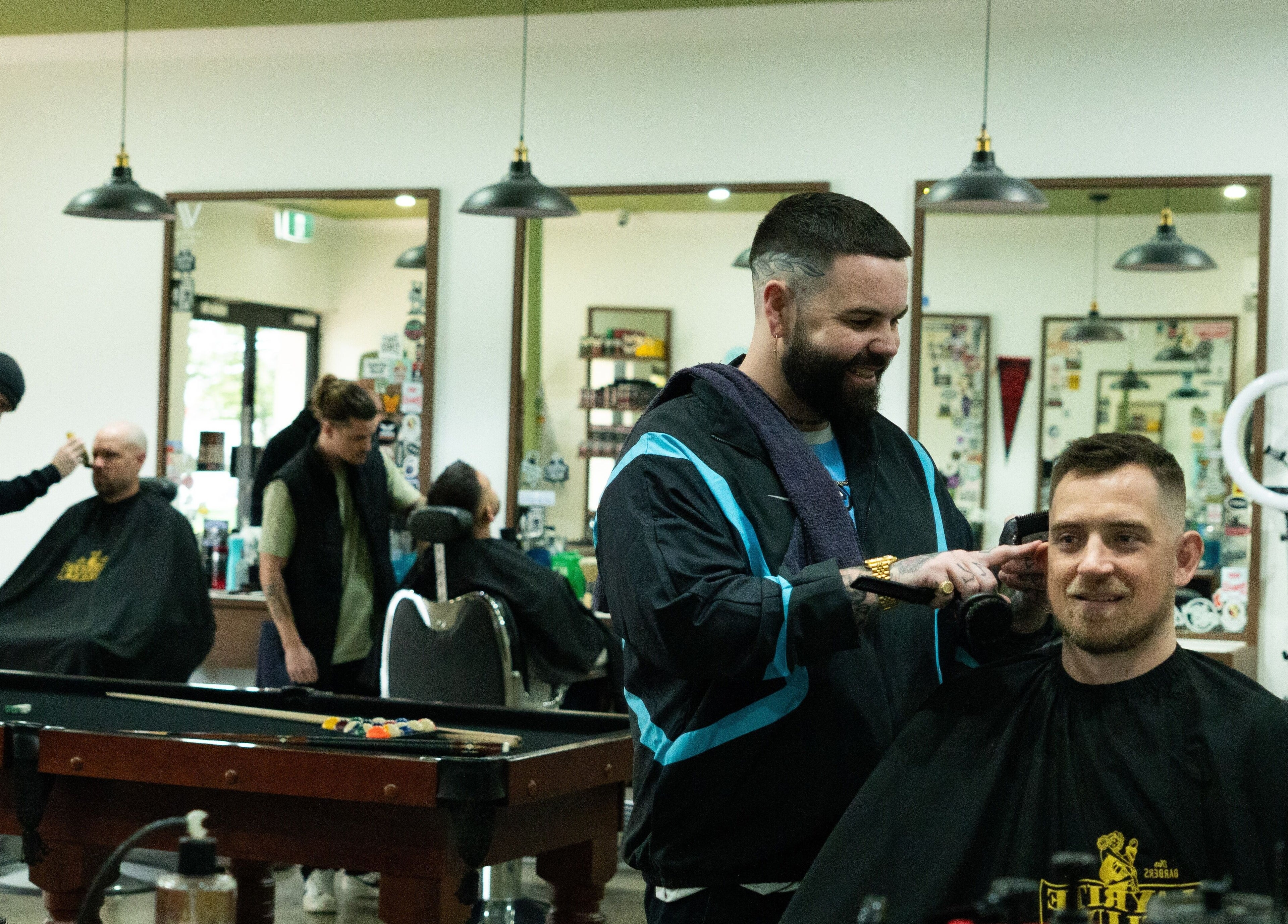 Stylishly modern interior of Nine Lives Barbershop, Paradise Point, Queensland, AU with engaged barbers.