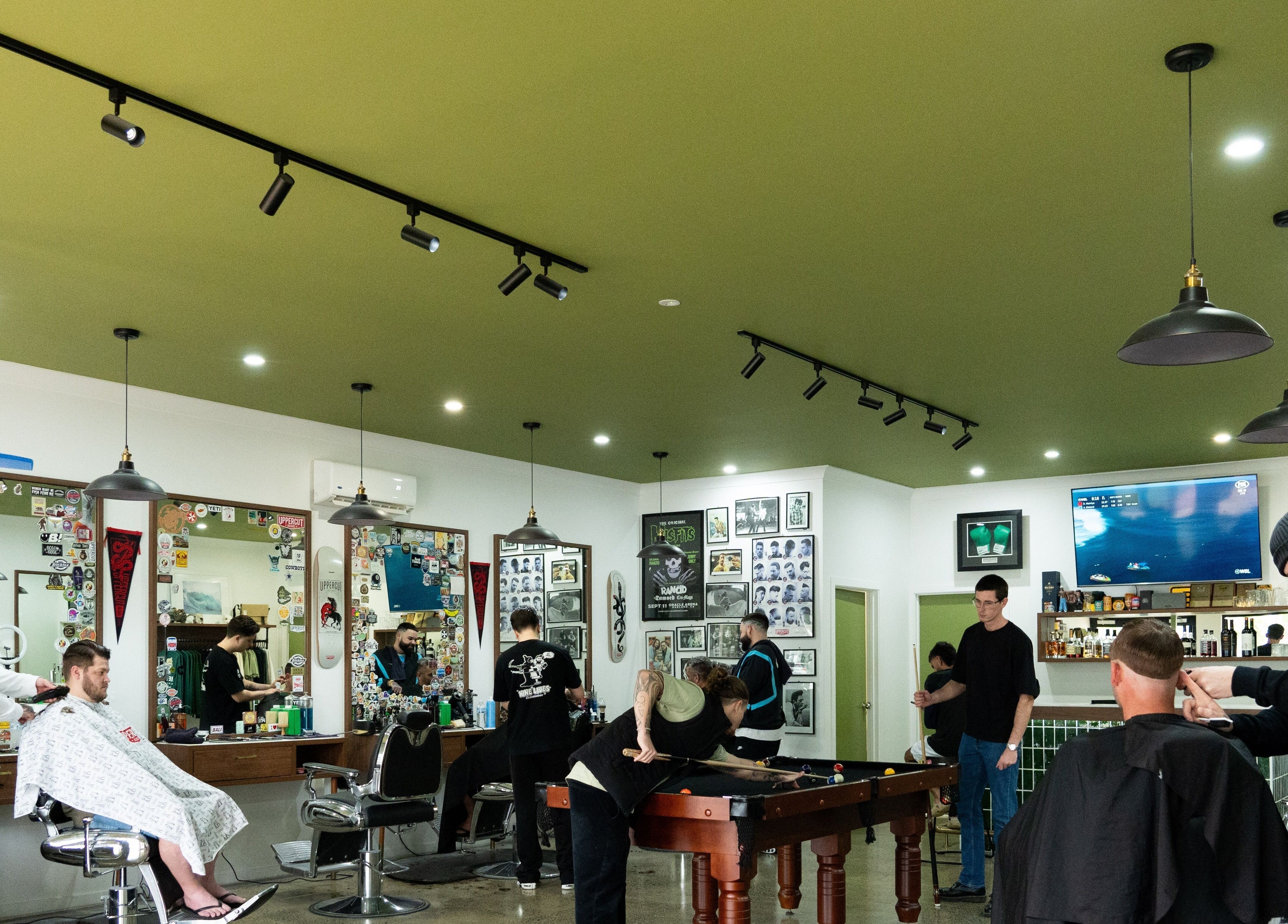 Nine Lives Barbershop in Paradise Point, Queensland, AU, bustling with clients and stylists in a modern setting.