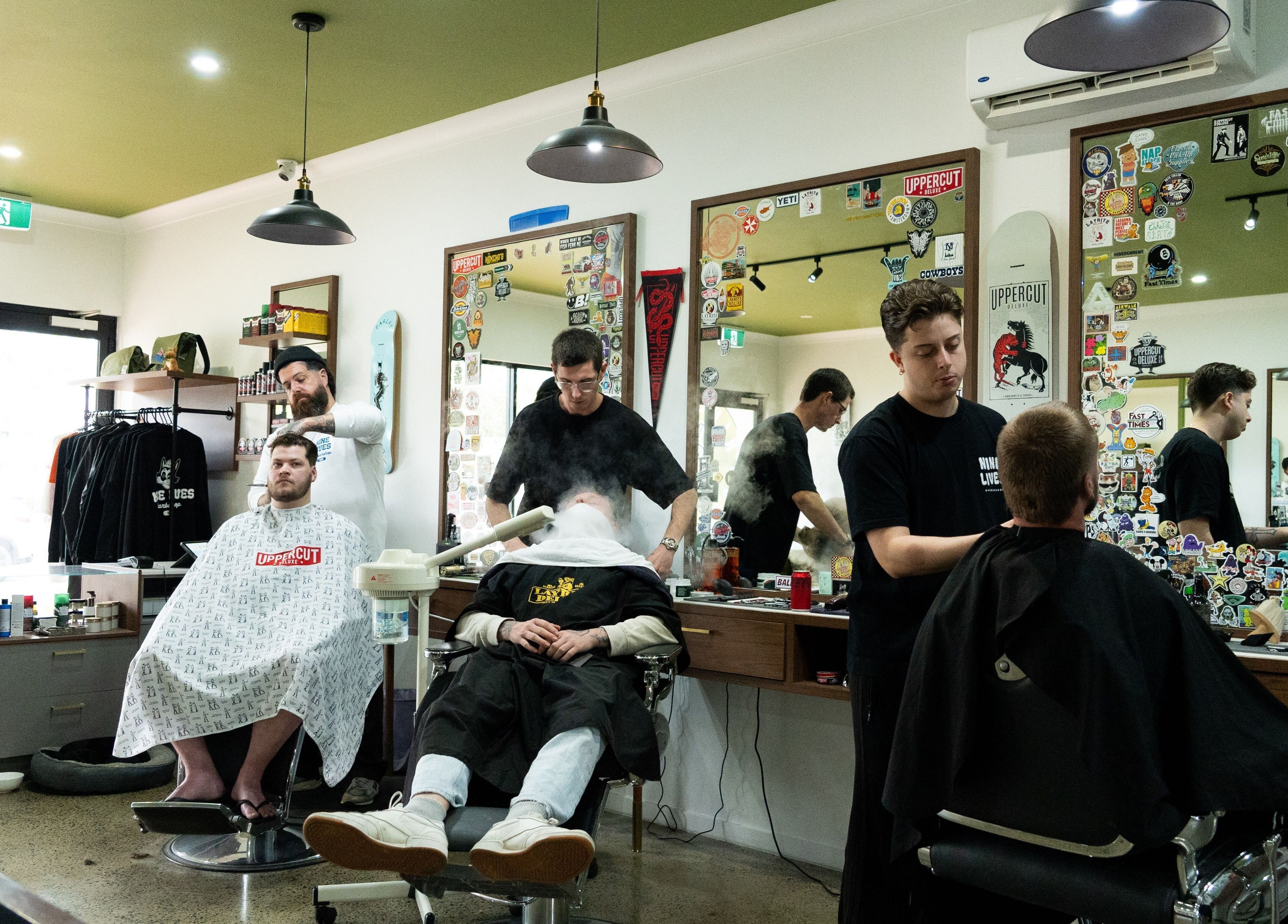 Stylish interior of Nine Lives Barbershop at Paradise Point, Queensland, AU with clients receiving haircuts.