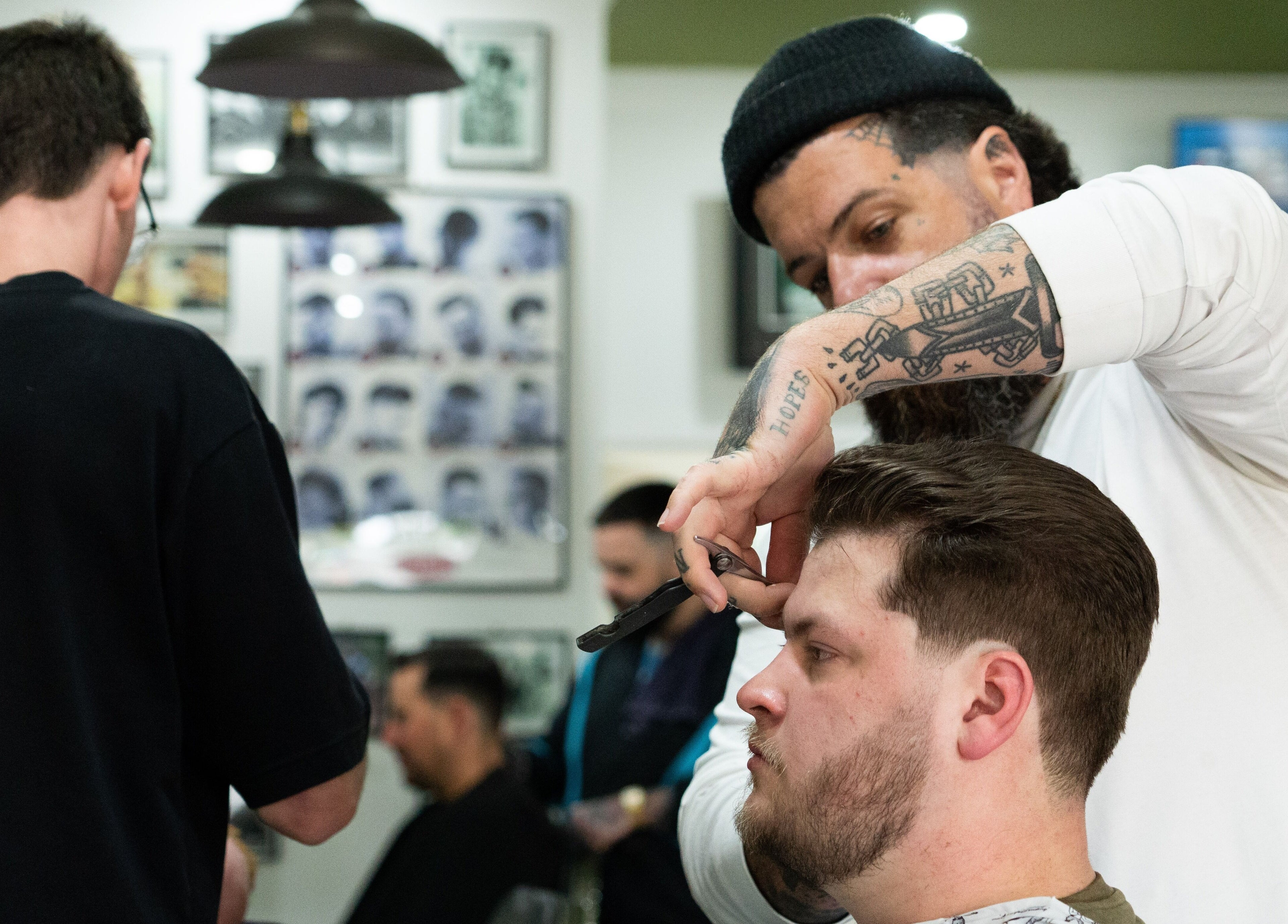 Barber expertly cuts hair at Nine Lives Barbershop, Paradise Point, Queensland, AU.