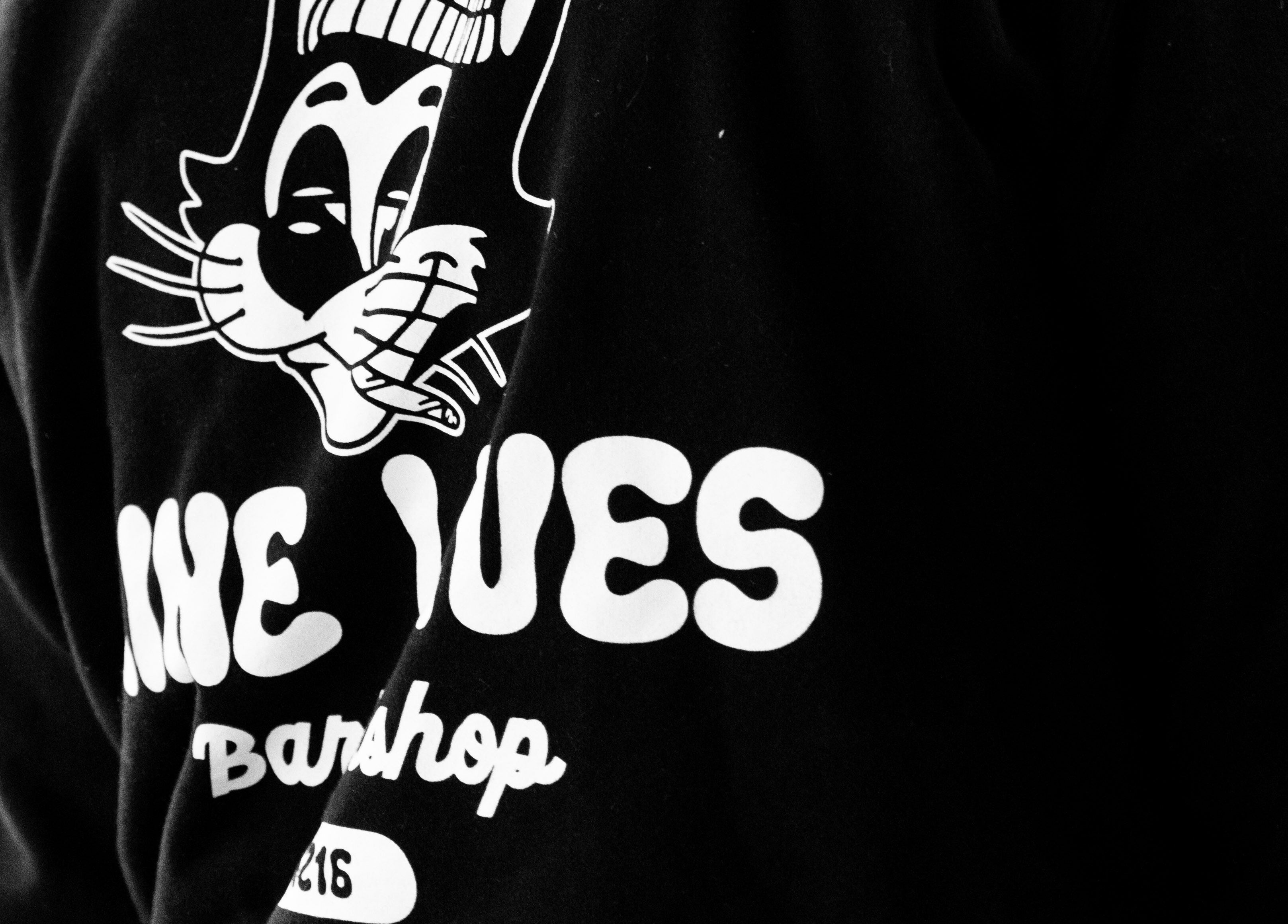 Nine Lives Barbershop logo on shirt at Paradise Point, Queensland, AU.