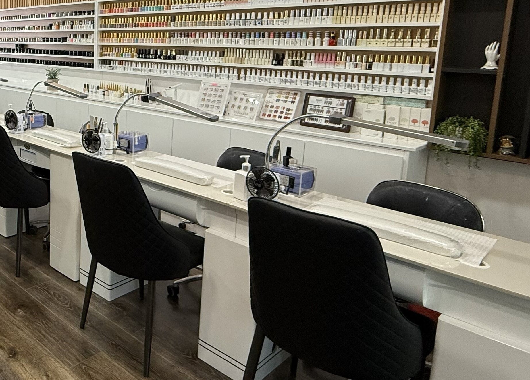 Modern nail stations at Lee Nails & Beauty, Melbourne, Victoria, AU, featuring luxurious seating and polish displays.