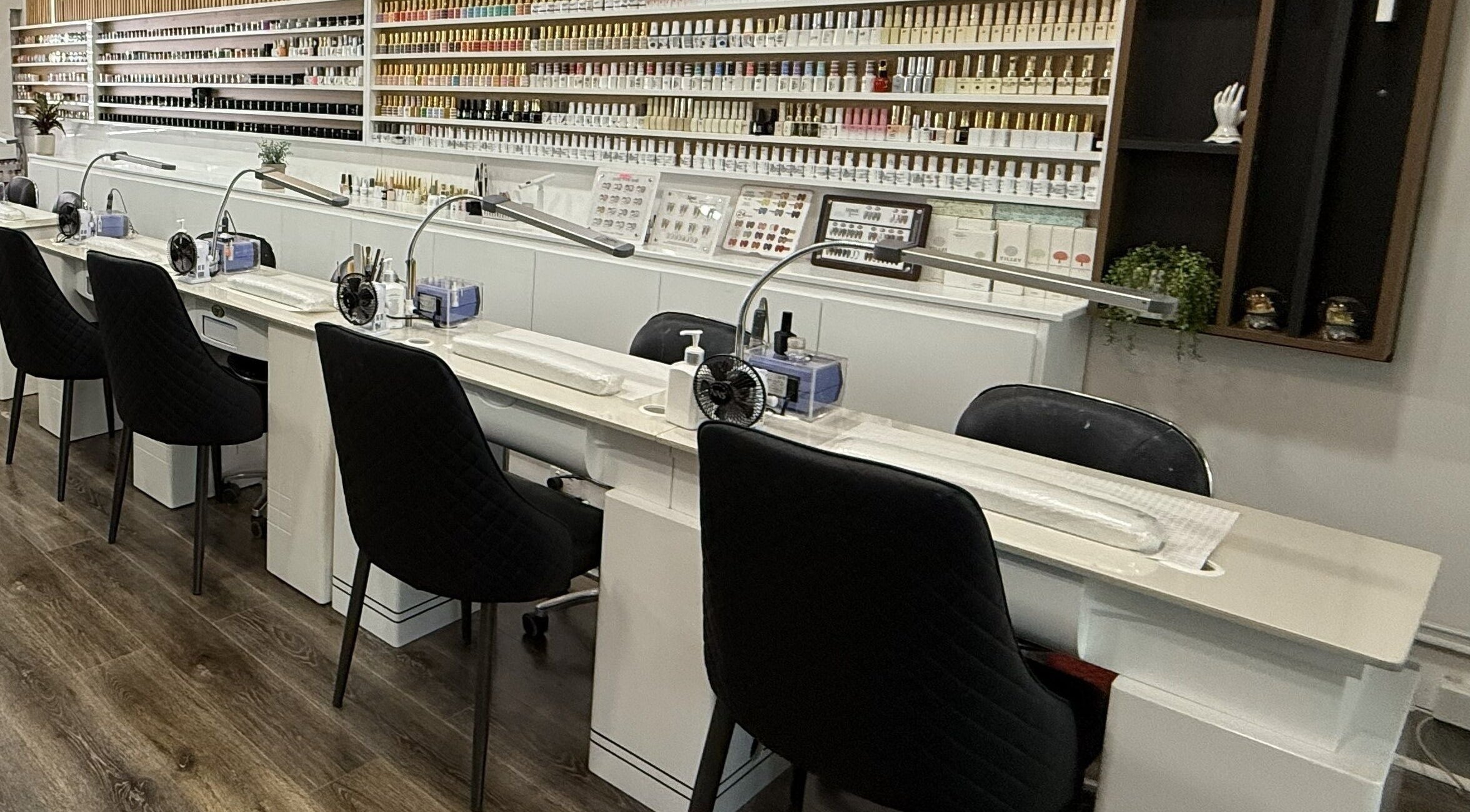 Modern nail stations at Lee Nails & Beauty, Melbourne, Victoria, AU, featuring luxurious seating and polish displays.