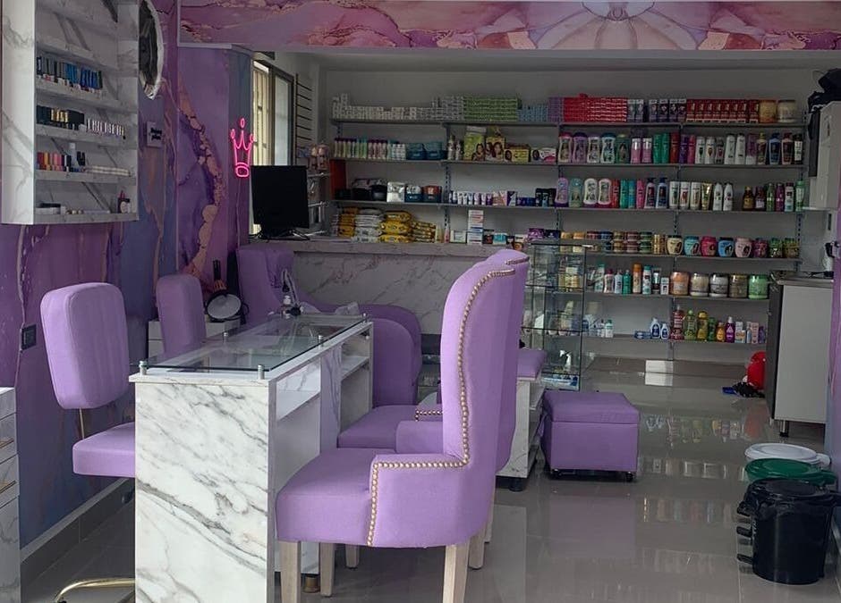 Interior de salón DIVINAS Y COSTOSAS en Medellín, Antioquia, CO. Sillas lilas y productos de belleza en estantes.