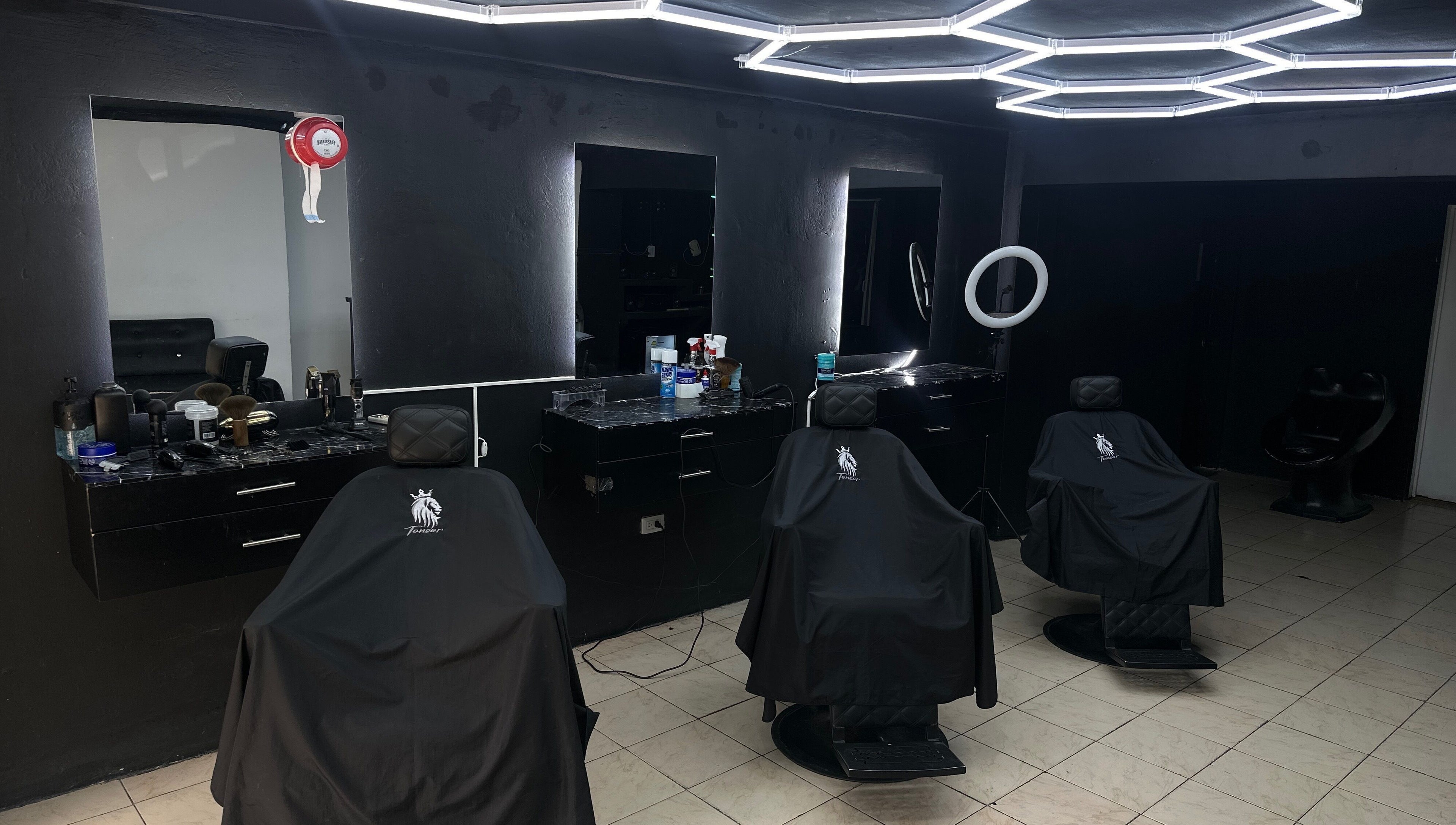 Interior moderno de Tonsor Studio en San Cristóbal, Táchira, VE con sillas y espejos iluminados.