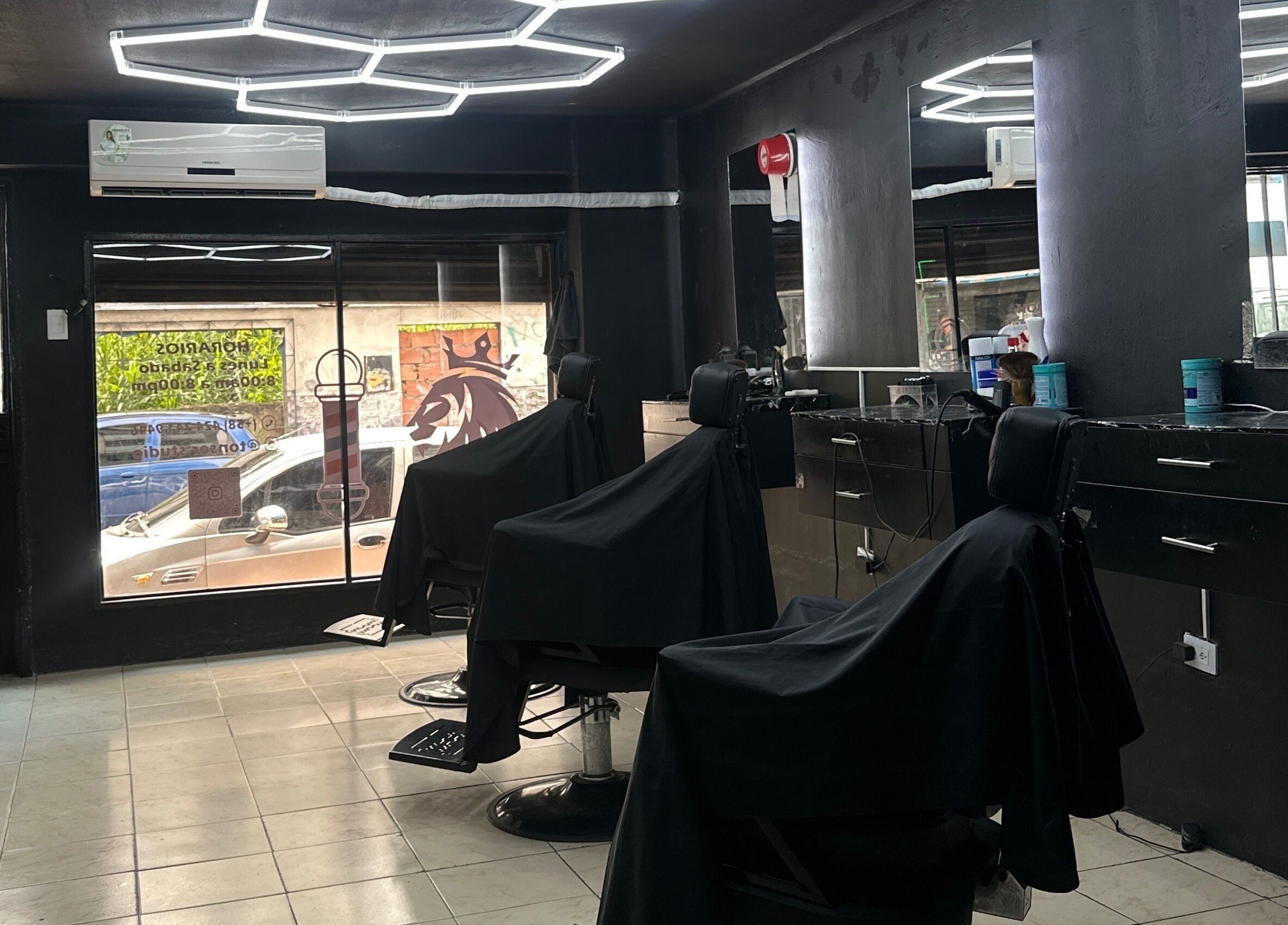 Interior de Tonsor Studio en San Cristóbal, Táchira, VE con sillas negras y estantes elegantes.