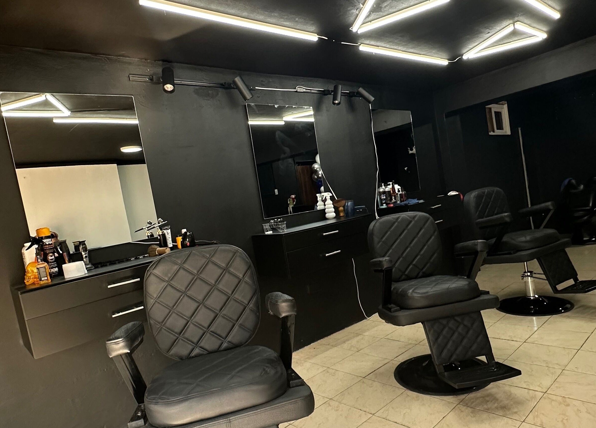 Interior moderno de Tonsor Studio en San Cristóbal, Táchira, VE con sillas de barbero y muebles elegantes.