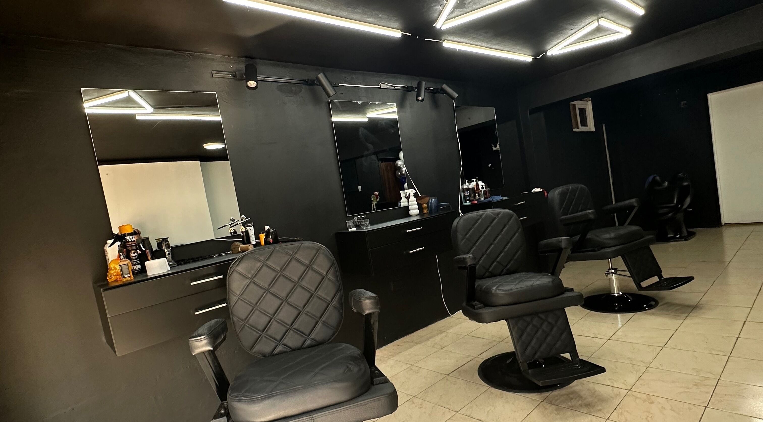 Interior moderno de Tonsor Studio en San Cristóbal, Táchira, VE con sillas de barbero y muebles elegantes.