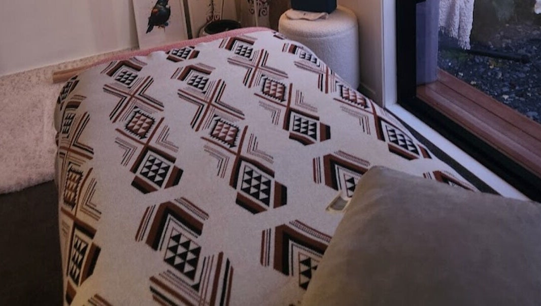 Relaxing room interior at Kotiora in Ōtaki, Wellington, NZ featuring a patterned throw and soft pillows.