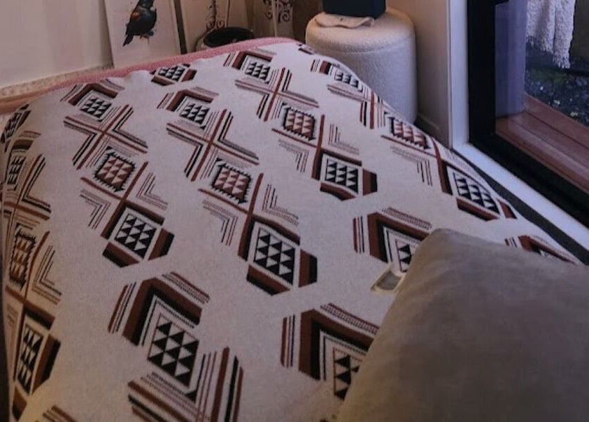Relaxing room interior at Kotiora in Ōtaki, Wellington, NZ featuring a patterned throw and soft pillows.