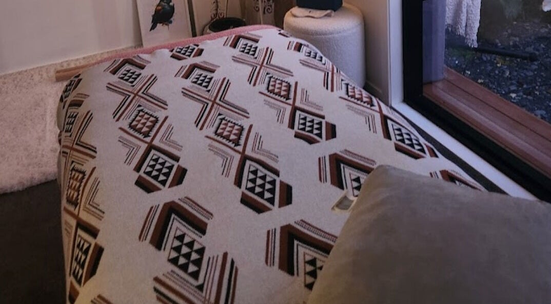 Relaxing room interior at Kotiora in Ōtaki, Wellington, NZ featuring a patterned throw and soft pillows.