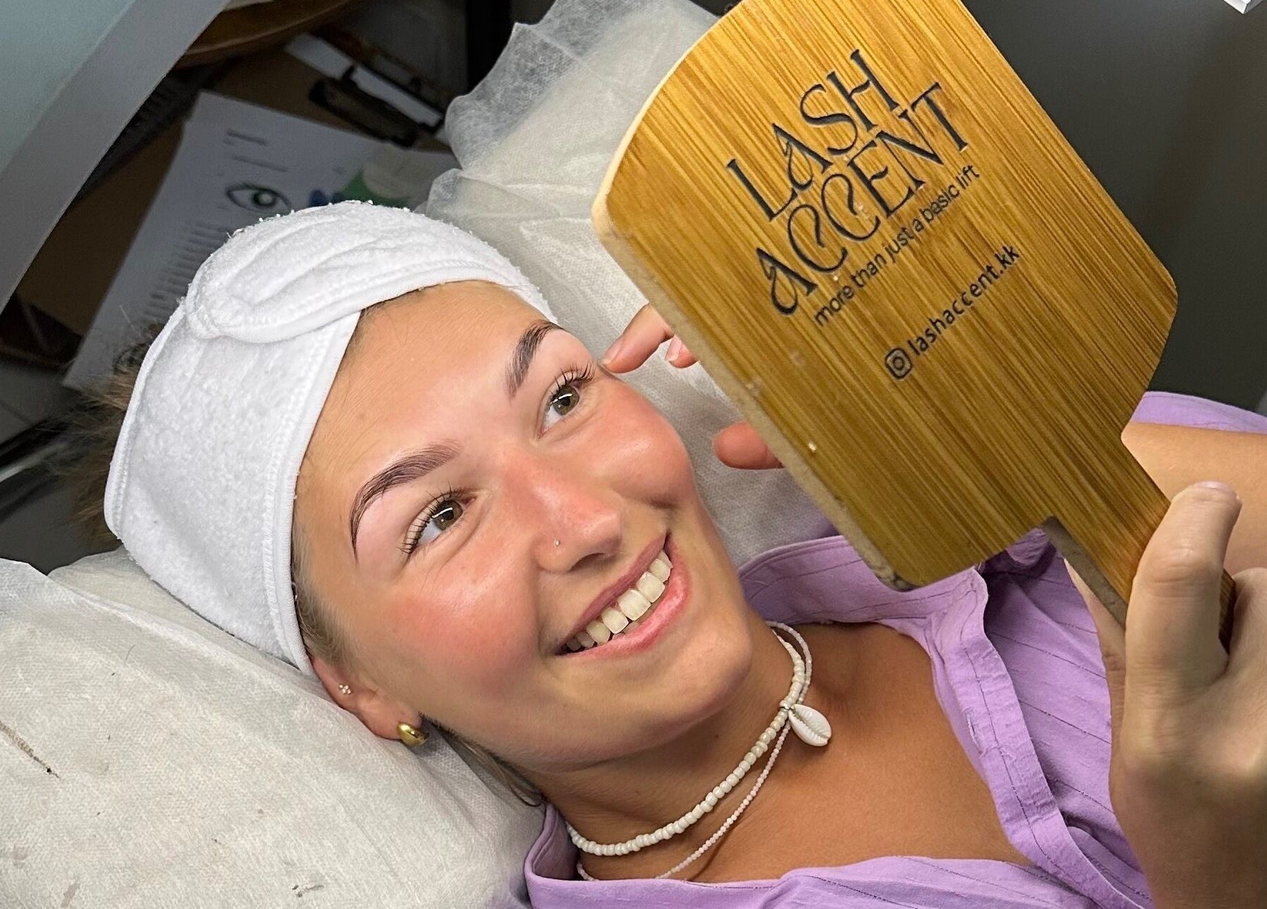 Happy client at Lash Accent, Kota Kinabalu, Sabah, MY, admiring new eyelashes in a handheld mirror.