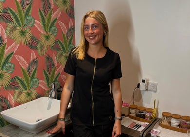Beauty therapist at Bronzed Beauty, Bangor, Northern Ireland, GB standing by a tropical-themed wall.