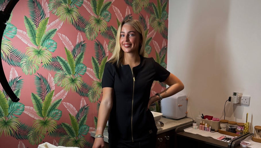 A stylish beautician at Bronzed Beauty, Bangor, Northern Ireland, GB, creating elegance amid tropical decor.