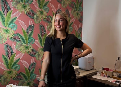 A stylish beautician at Bronzed Beauty, Bangor, Northern Ireland, GB, creating elegance amid tropical decor.