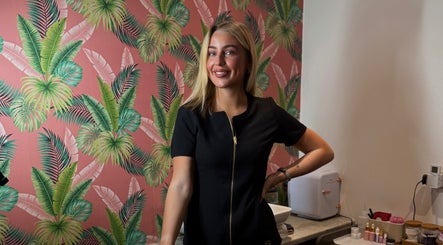Staff member at Bronzed Beauty, Bangor, Northern Ireland with a tropical background and beauty products.