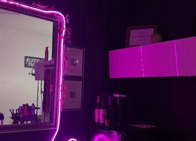 Stylish interior of NanoGlow Hair Co. salon, Fort Erie, Ontario, CA, featuring neon-lit mirror and decor.