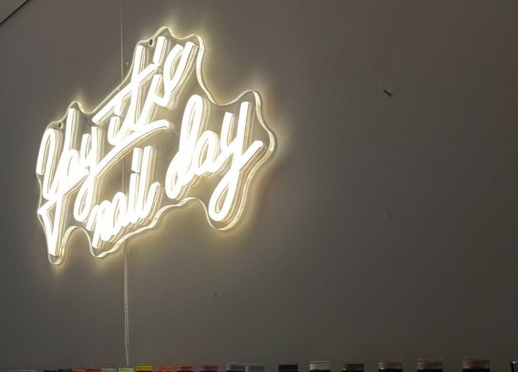 Neon sign 'Yay it's nail day' at Milkshake Nails & Tan, Waitara, Taranaki, NZ, with colorful nail polish display.
