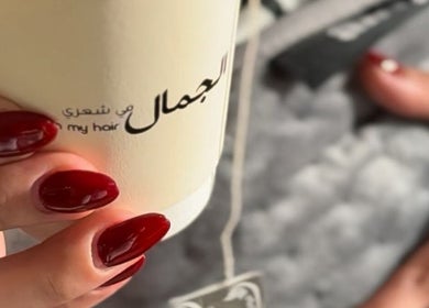 Close-up of manicured nails holding a branded cup at Beauty in my hair, Riyadh, Riyadh Province, SA.