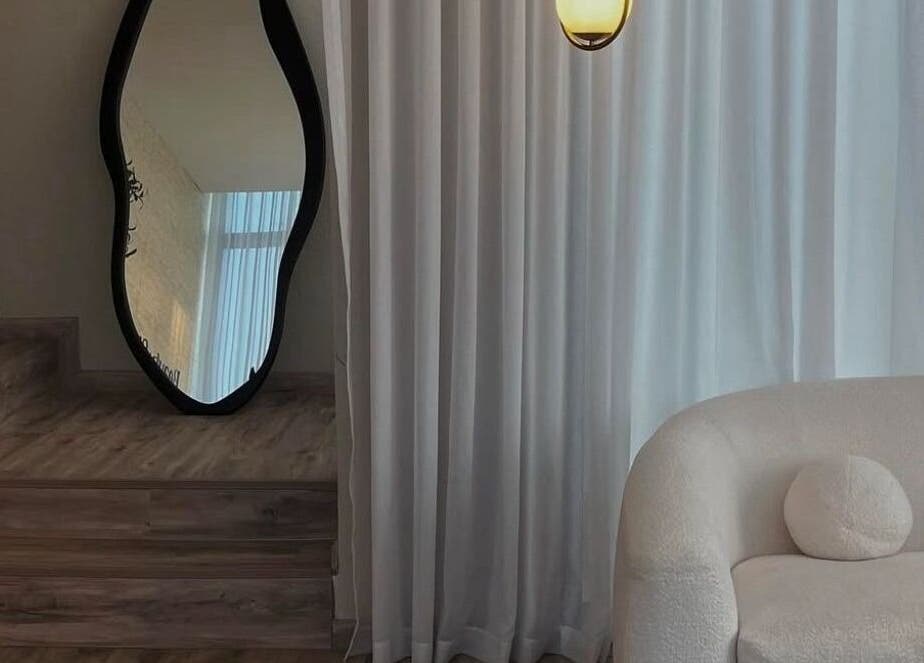 Chic interior of Beauty In My Hair in Riyadh, showcasing a plush sofa and artistic mirror.