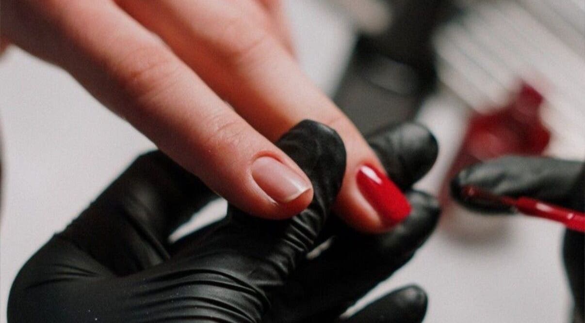 Manicure in progress at Beauty In My Hair, Riyadh, Riyadh Province, SA. A nail technician applies red polish.