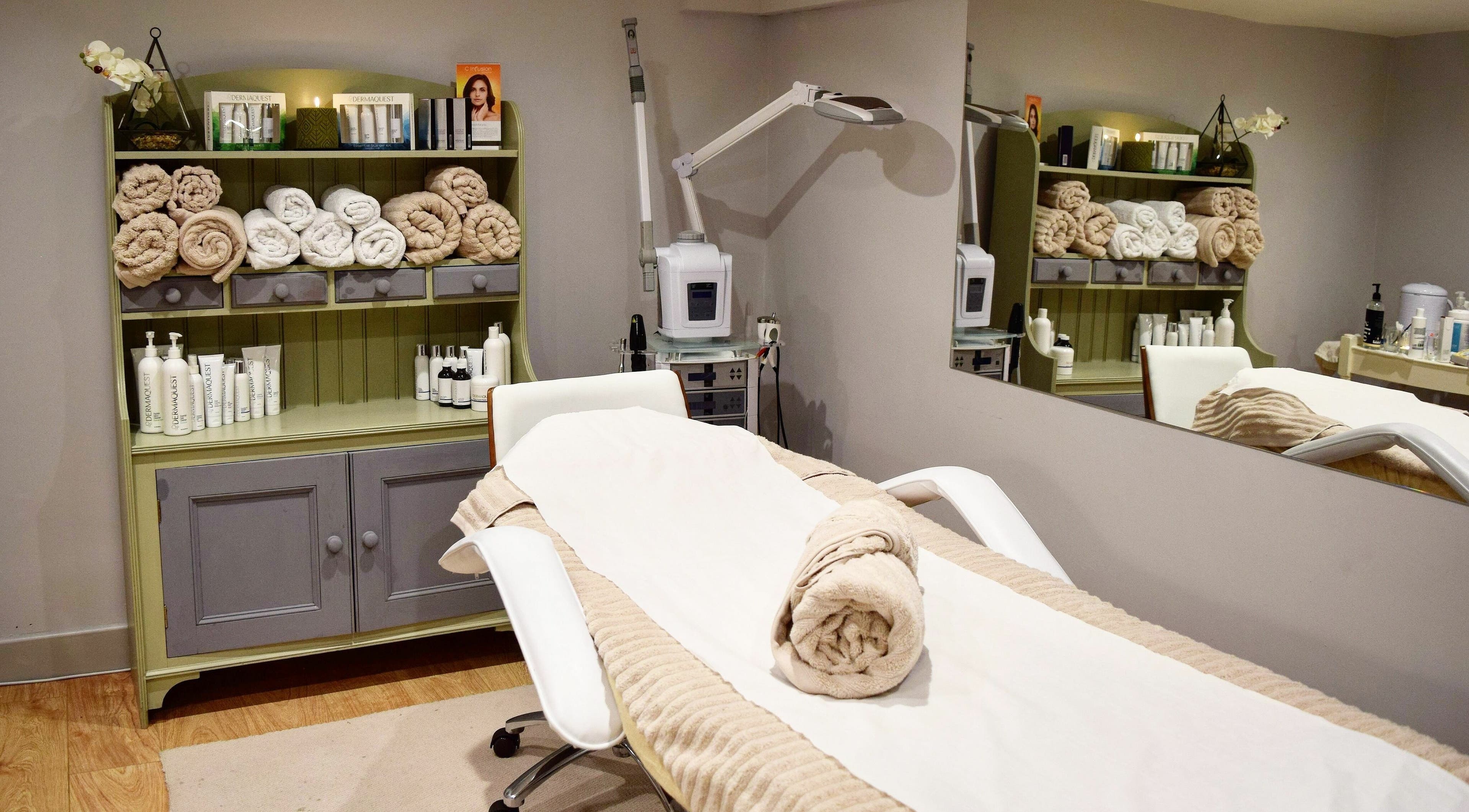 Tranquil spa room at Holimed Beauty, Richmond, England, GB featuring a treatment bed and neatly arranged towels.
